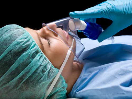 General anesthesia sedation gloved hand holds breathing mask to sleeping patients face