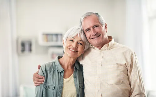 Older couple hugging smiling GettyImages 861202784